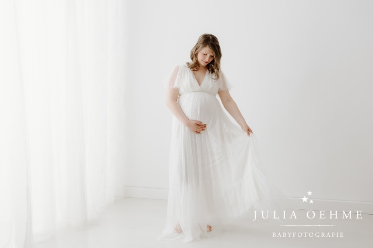 schwangere im langen weißen kleid bei babybauchsession in leipziger fotostudio